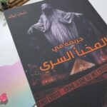 Book cover of Murder in the Secret Hideout by Ghassan Nabhan, featuring a ghost over Paris landmarks and Louvre Pyramid .